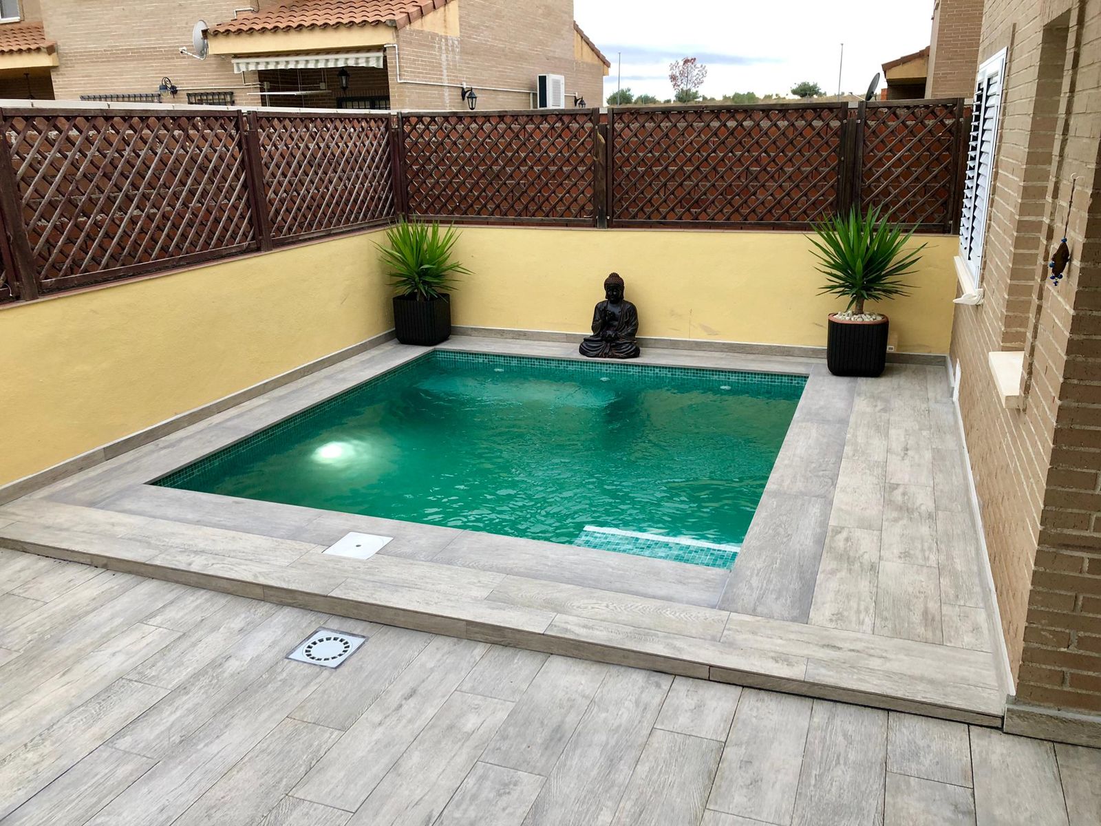 Piscina de obra terminada con solado porcelánico y jardín